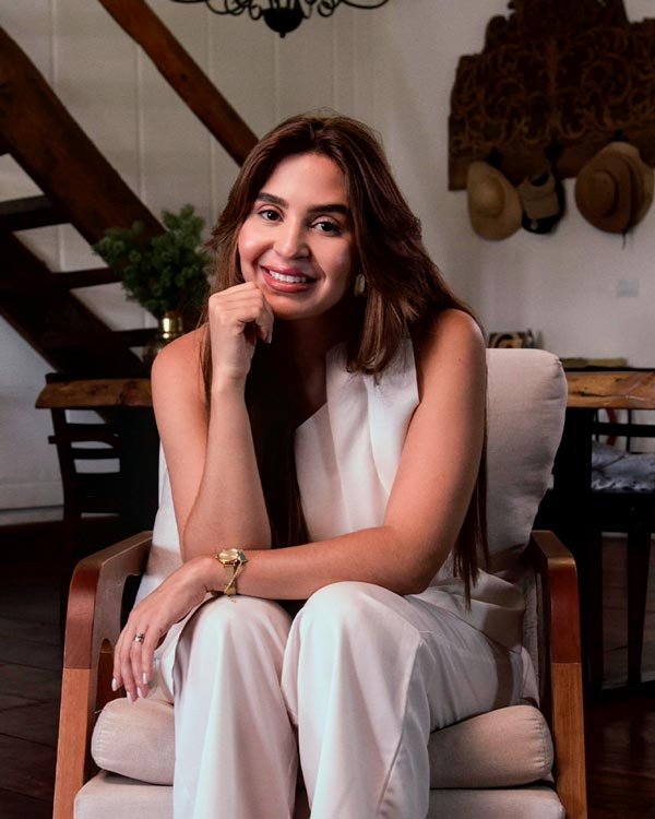 Gabi Mattos sentada, sorrindo, com roupa branca